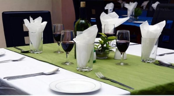 A table set for dining with wine glasses, a bottle, and a green tablecloth.