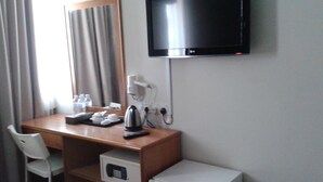 A hotel room with a desk, a television mounted on the wall, a coffee maker, a microwave, and a small refrigerator. - De Spring Hotel (Kuantan)