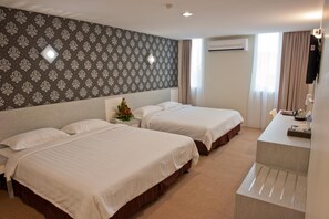 Une chambre d’hôtel avec deux lits, un bureau, un miroir et un papier peint à motifs.