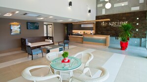 A modern hotel lobby with a reception desk, seating area, and a glass table with chairs. - De Spring Hotel (Kuantan)