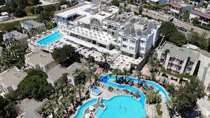 A large hotel with multiple swimming pools, including a central pool and a smaller pool surrounded by palm trees. - Phoenix Sun Hotel (Bodrum)
