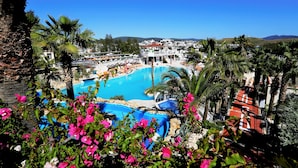 A resort with a large pool, palm trees, and a view of the surrounding landscape. - Phoenix Sun Hotel (Bodrum)