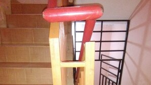 A wooden staircase with a metal handrail and a metal railing at the top. - Veroanto Hotel (Siaya)