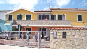 A two-story building with a stone facade, a balcony, and a gated entrance. - Terrazze sul Mare Alla Ciaccia - Apartment 3 (Valledoria)