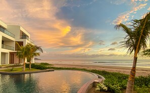 Een modern resort met zwembad, uitzicht op het strand en palmbomen.