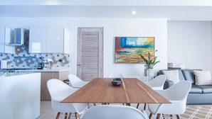 Une cuisine moderne avec des meubles blancs, une table à manger en bois et des chaises blanches.