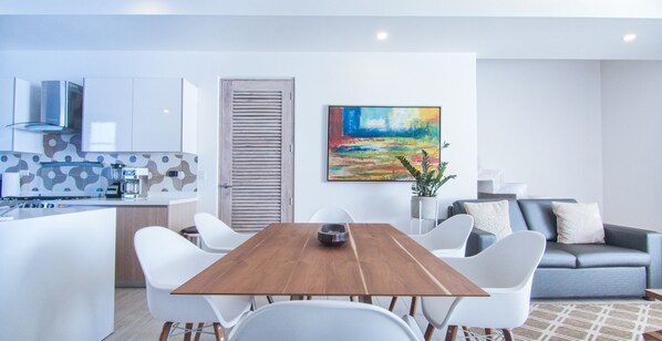 Une cuisine moderne avec des meubles blancs, une table à manger en bois et des chaises blanches.