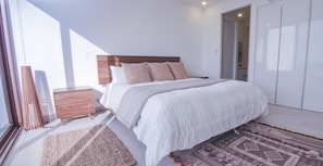 Un dormitorio moderno con una cama grande, cabecera de madera y alfombra estampada.