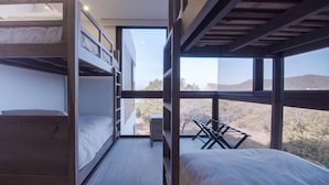 Une chambre avec des lits superposés offrant une vue sur un paysage montagneux grâce à de grandes fenêtres.