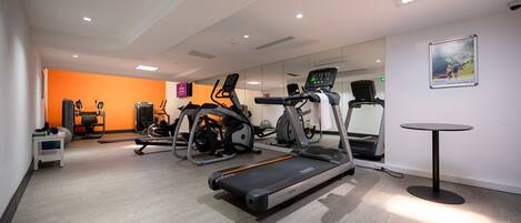 A modern gym with treadmills, elliptical machines, and a rowing machine.