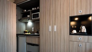 A compact kitchen with built-in appliances, a microwave, and a small refrigerator.