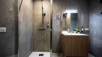 A modern bathroom with a glass-enclosed shower, a wooden vanity, and a large mirror.