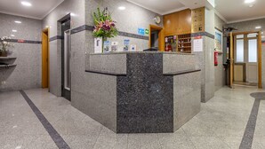 A reception area with a marble counter, a clock, and a fire extinguisher. - Residencial Horizonte (Lisbon)
