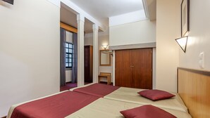 A hotel room with a large bed, a wooden wardrobe, a mirror, and a small table. - Residencial Horizonte (Lisbon)