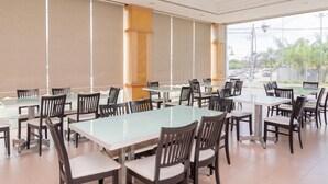 A spacious indoor dining area with multiple tables and chairs, large windows, and a view of the outside. - Pelican Hotel (Batu Pahat)