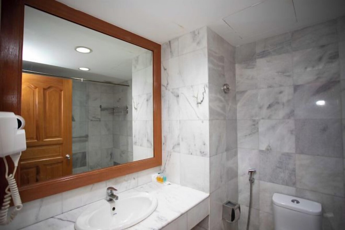 A bathroom with a marble sink, a large mirror, and a shower.