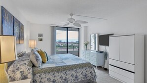 A bedroom with a bed, a dresser, a television, and a balcony with a city view. - Anchorage Resort 6th Floor 2 bedroom Condo on Siesta Key (Siesta Key)