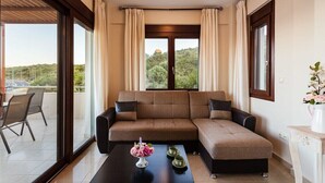 Een moderne woonkamer met een bruine hoekbank, een zwarte salontafel met een bloemdecoratie, en uitzicht op een groen landschap door grote ramen.
