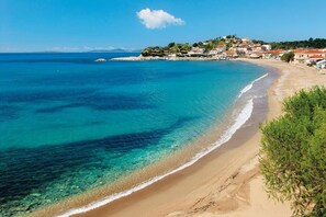 Un pueblo costero con aguas azul cristalino, playas de arena y edificios de techos rojos.