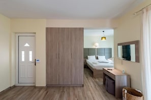 Una camera d'albergo con un letto, un comodino, una lampada, un armadio e uno specchio.