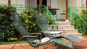 A wooden deck with two green lounge chairs, a table, and a covered area with a tiled roof. - Coastal Dreamy Retreat, Dive in Dimitra's Paradise (Finikounta)