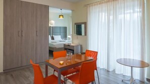 Hotellihuone, jossa on ruokailutila, sänky, vaatekaappi ja kylpyhuone, joka näkyy avoimesta ovesta.