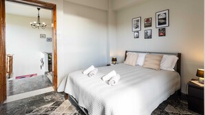 A hotel room with a large bed, a chandelier, and framed pictures on the wall. - Sunset Serenity - Kardamili Seaside Getaway (Kardamyli)