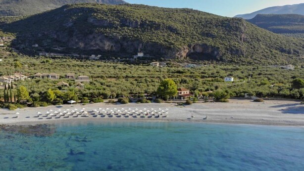 A coastal resort with clear blue waters, a sandy beach, and a backdrop of green hills. - Sunset Serenity - Kardamili Seaside Getaway (Kardamyli)