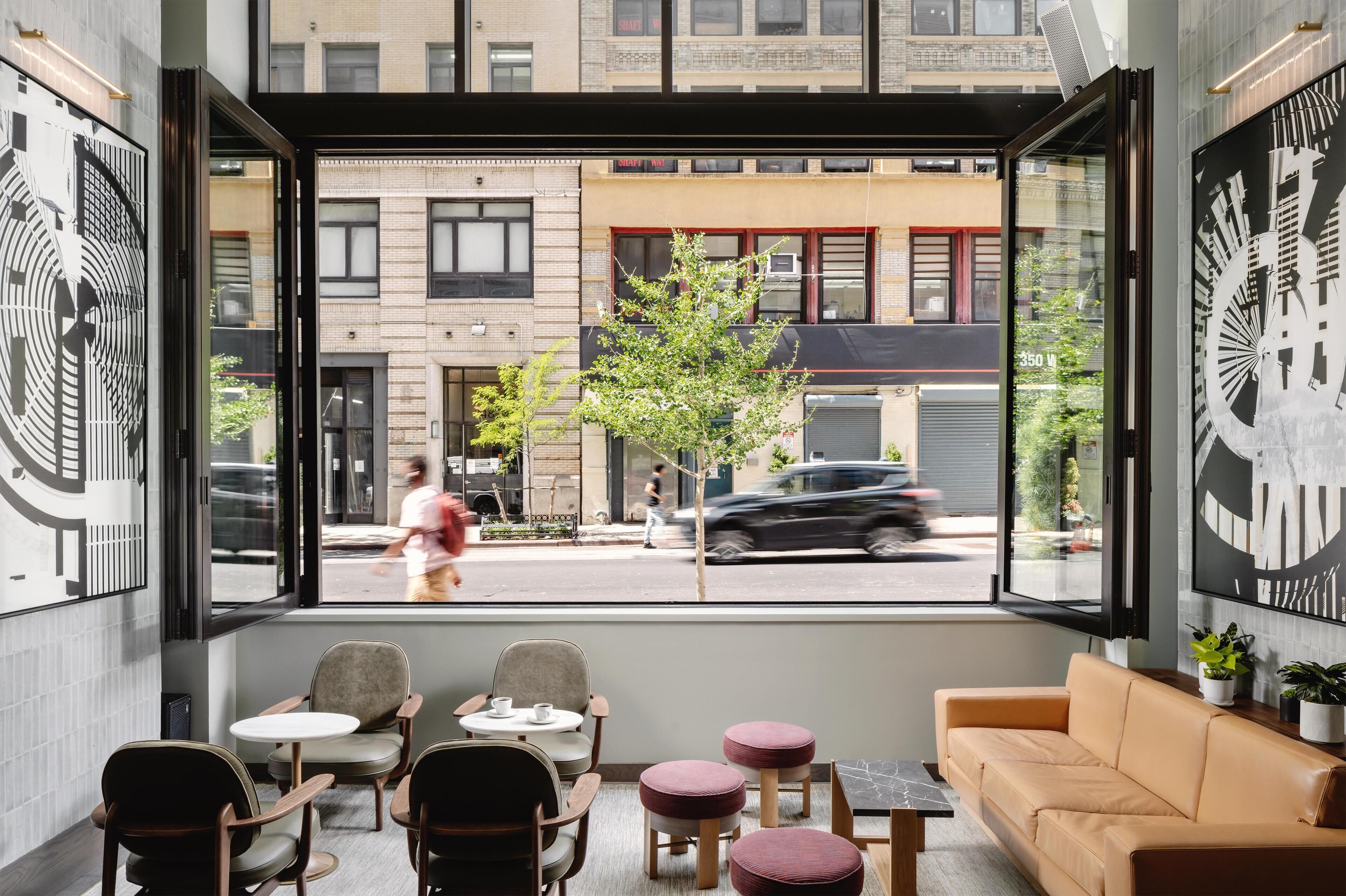 A modern interior with a seating area, a sofa, and a large window overlooking a street.