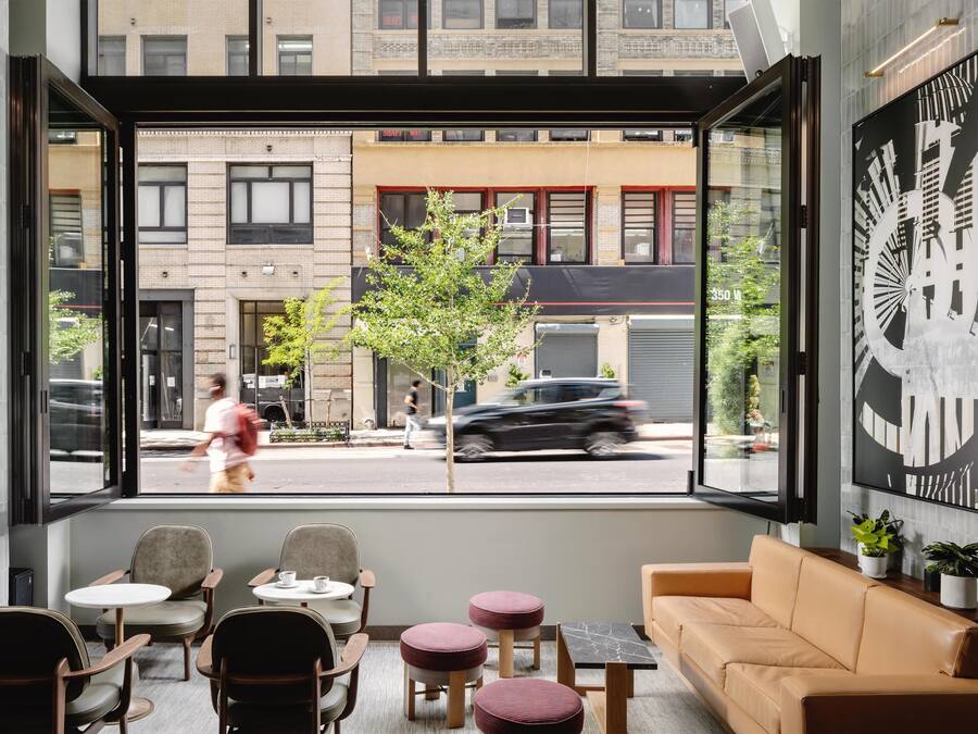A modern interior with a seating area, a sofa, and a large window overlooking a street.