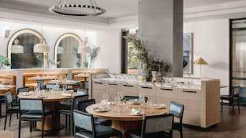 A modern restaurant with round tables, black chairs, and a marble counter.