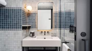 Un baño moderno con un lavamanos blanco, un espejo y un perchero para toallas.