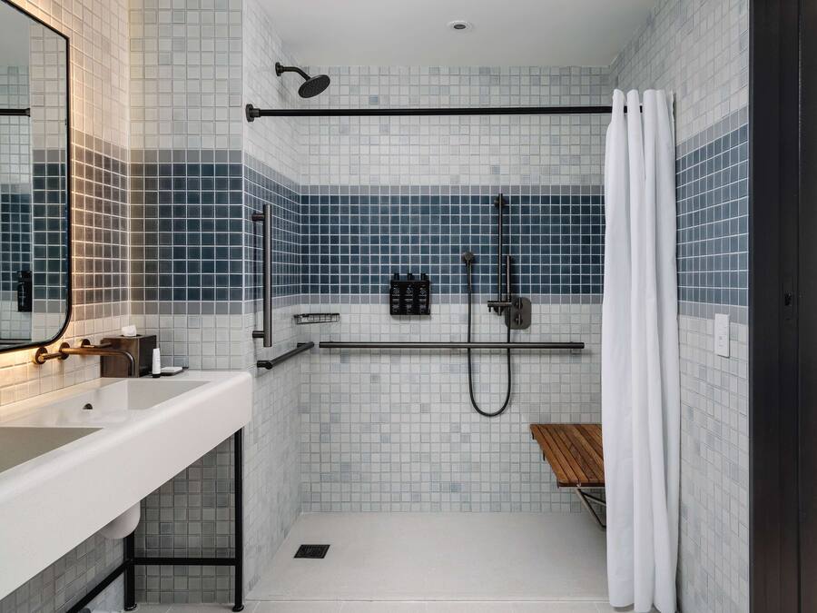 Un baño moderno con un lavabo blanco, una ducha con puerta de cristal y un espejo sobre el lavabo.