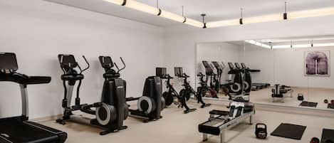 A modern gym with various exercise equipment, including treadmills, stationary bikes, and weights.