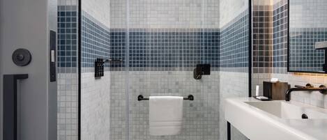 Un baño moderno con cabina de ducha de vidrio, un lavabo blanco y un perchero para toallas.
