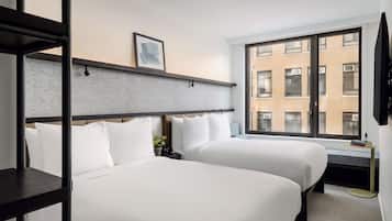 A hotel room with two beds, a large window with a city view, a small table, and a TV mounted on the wall.