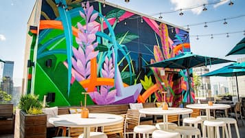 Un mural vibrante con motivos florales y geométricos abstractos en la pared exterior de un edificio.