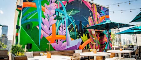 Un mural vibrante con motivos florales y geométricos abstractos en la pared exterior de un edificio.