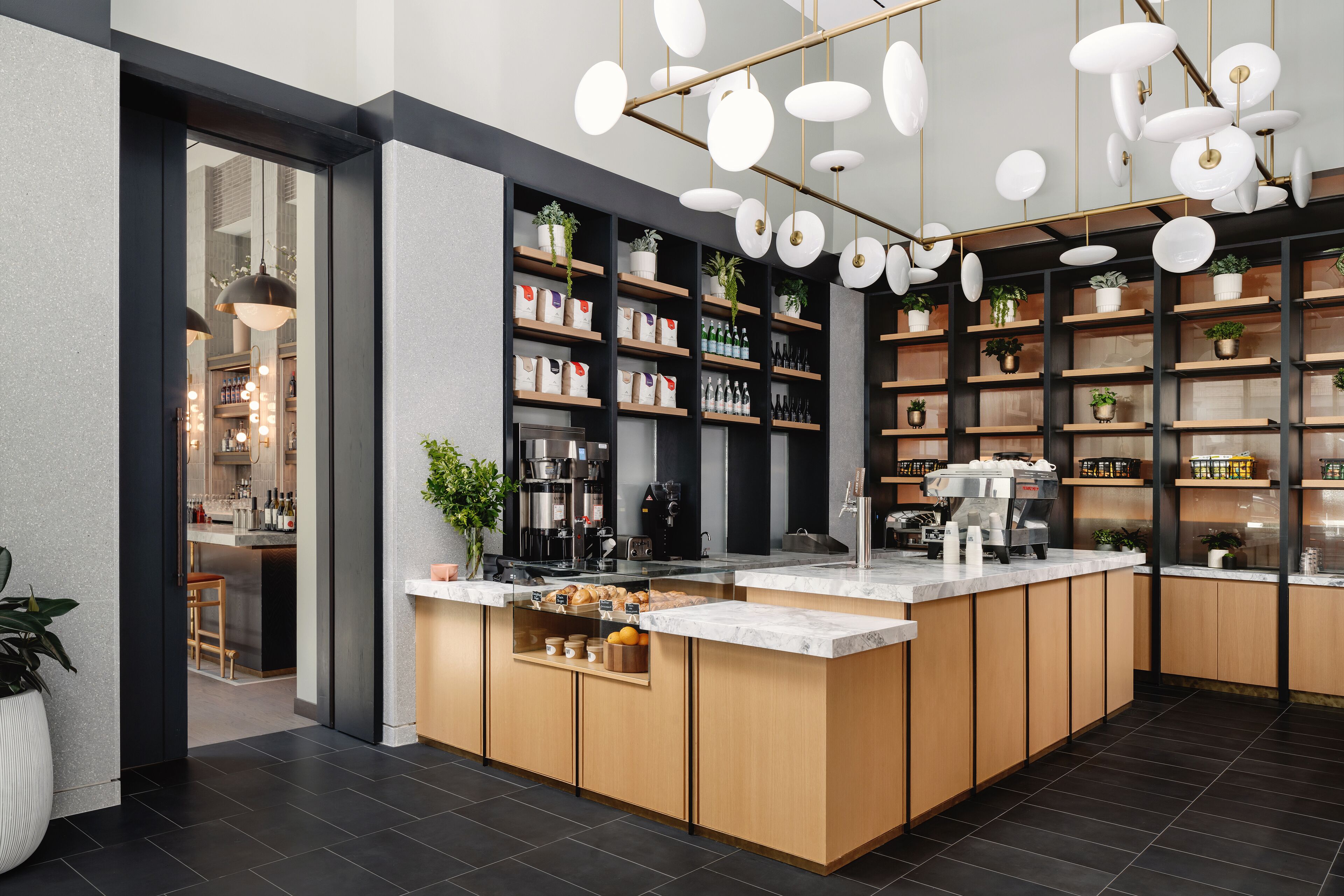 A modern kitchen with a central island, built-in shelves, and hanging pendant lights.