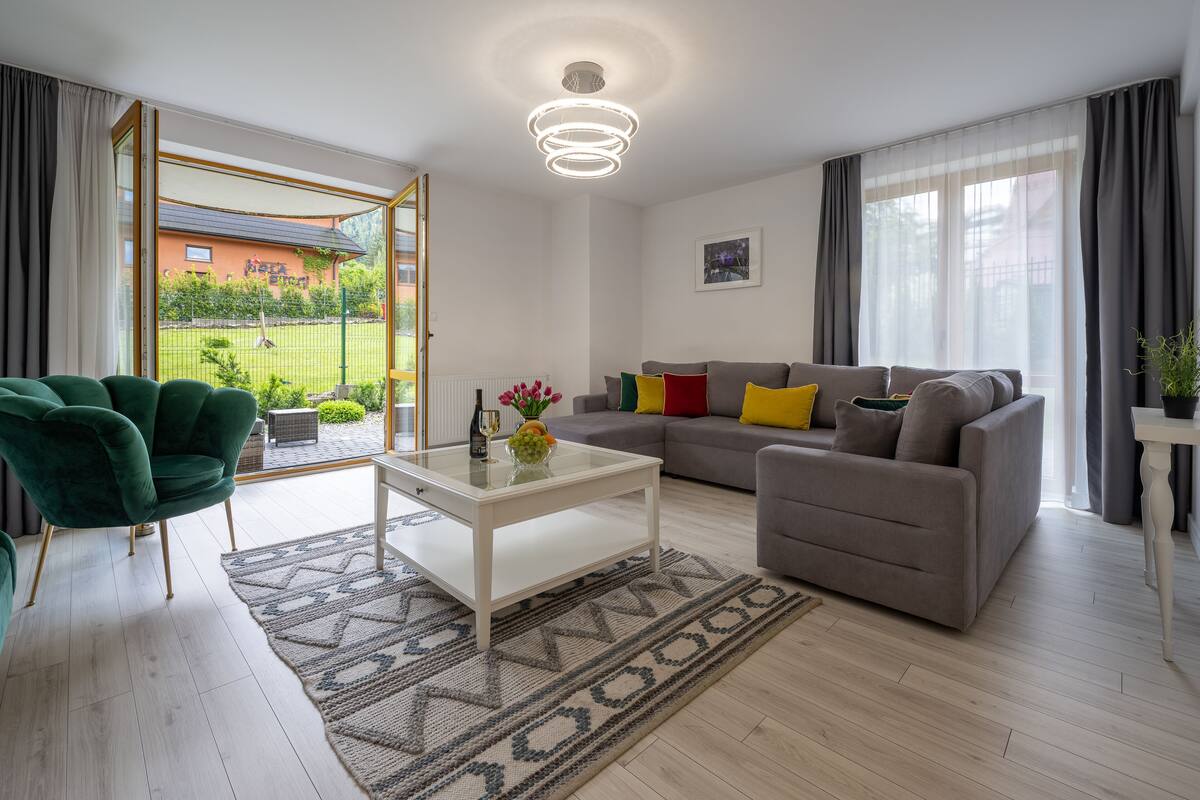 A modern living room with a sofa, armchairs, a coffee table, and a view of the outside.