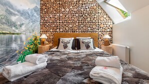 A bedroom with a mountain lake view, a wooden log wall, a bed with deer pillows, and a skylight. - Apartamenty Bory 6a (Zakopane)