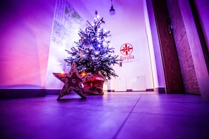 A Christmas tree with lights and ornaments in a lobby area with a sign reading "Rory6a Parliament".