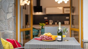 A dining table with a bottle of champagne, a glass, a plate of fruit, and a red napkin. - Apartamenty Bory 6a (Zakopane)