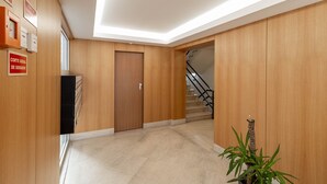 A modern hotel lobby with wooden paneling, a staircase, and a potted plant. - Savory Black Apartment, Sete Rios, Lisbon!New! (Lisboa)