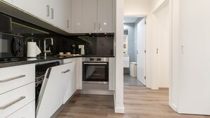 A modern kitchen with white cabinetry, a black countertop, and a built-in oven. - Savory Black Apartment, Sete Rios, Lisbon!New! (Lisboa)