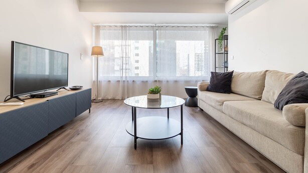 A modern living room with a flat-screen TV, a round coffee table, a sofa, and a large window with curtains. - Savory Black Apartment, Sete Rios, Lisbon!New! (Lisboa)