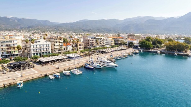 A marina with boats docked, a waterfront promenade, and buildings with balconies overlooking the water.