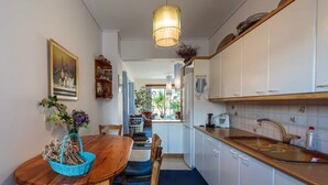 A compact kitchen with white cabinets, a wooden countertop, and a hanging light fixture.
