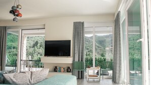 A modern bedroom with a large window, a flat-screen TV, and a balcony with a view of the countryside. - Villa Hvar Beauty with Swimming Pool (Jelsa)