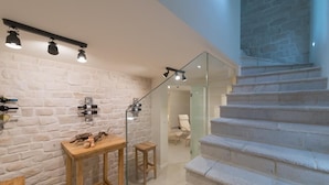 A modern interior with a stone wall, a wooden table with decorative items, and a staircase with glass railings. - Villa Hvar Beauty with Swimming Pool (Jelsa)